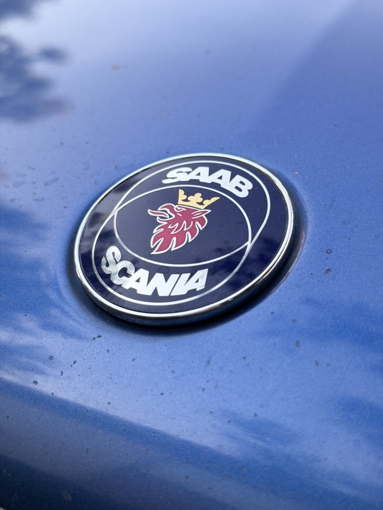 Saab-Scania hood emblem set into the Viggen’s Lightning Blue metallic hood, showing the metallic flake and reflections
